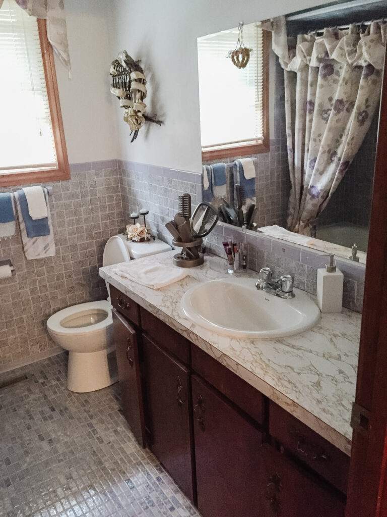 1970s bathroom vanity with dark wood, laminate counters, and purple floor and wall tile