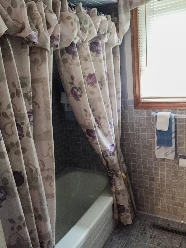 1970s purple tiled bathroom with puffy floral shower curtain.