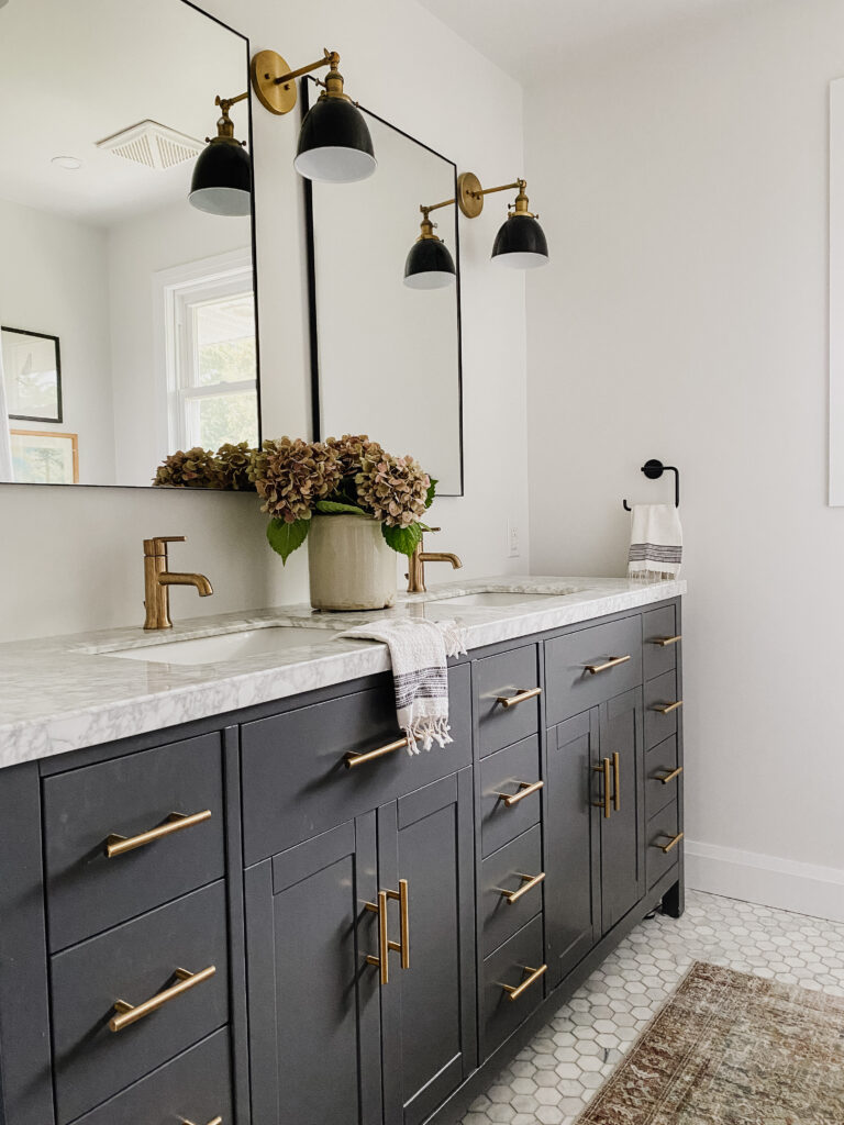 Dark grey double vanity with marble countertop and brass hardware.