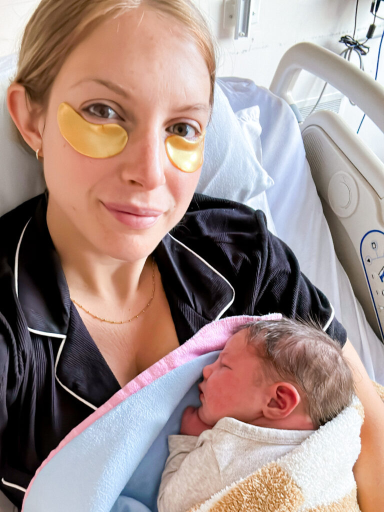 New mom in hospital bed with newborn baby wearing Stella & Grace eye patches under her eyes.