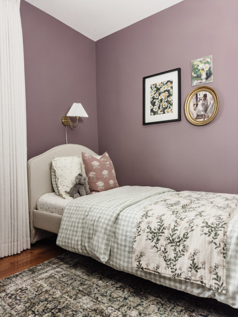 Girls room with upholstered twin sized bed, purple walls, and a gallery wall with painted florals and ballerinas.